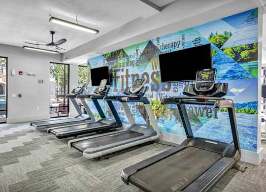 A gym with treadmills and a wall mural.