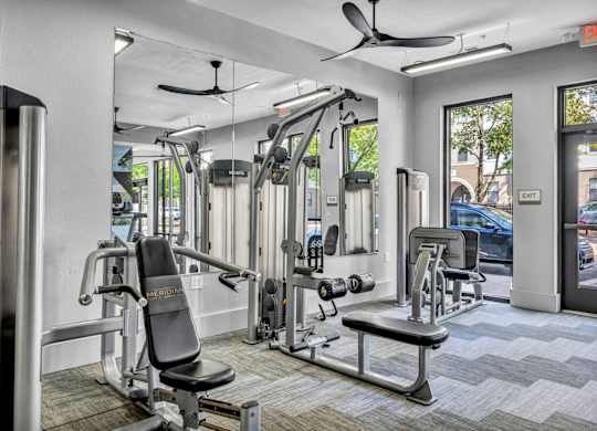 A gym with a variety of equipment including a weight bench, a leg press machine, and a cable machine.