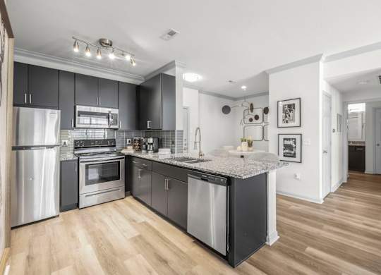 A modern kitchen with a refrigerator, oven, and sink.