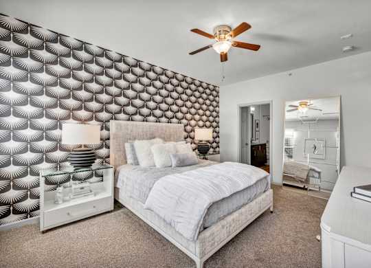 A bedroom with a bed, dresser, and a ceiling fan.