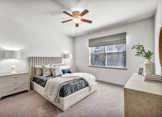 A bedroom with a bed, nightstand, and window.