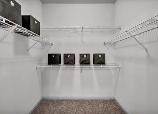 A room with a white wall and a shelf with four speakers on it.