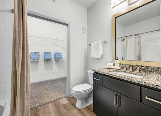 A bathroom with a toilet, sink, and mirror.