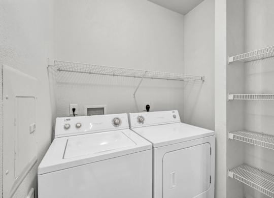 Two white front loading washing machines in a laundry room.