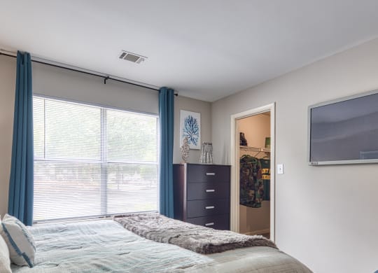 a bedroom with a large window and a bed with blue curtains