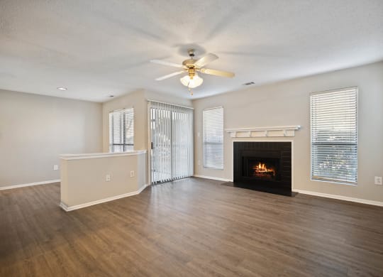 an empty living room with a fireplace and a ceiling fan
