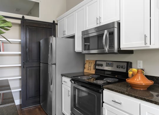 a kitchen with black appliances and white cabinets and a refrigerator at Hayden Lofts, Dublin, Ohio