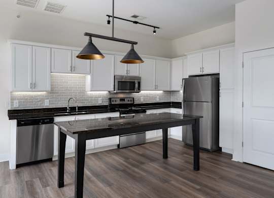 A modern kitchen with a black table and stainless steel appliances.