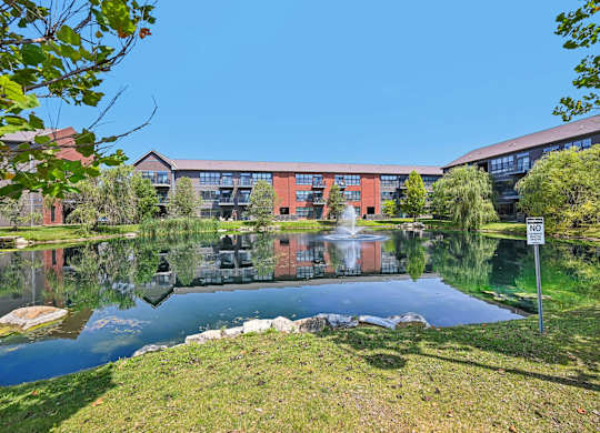 A building with a red brick exterior is reflected in a body of water.