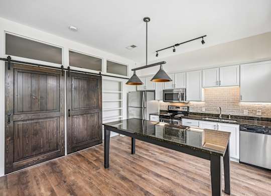 A modern kitchen with a dark wood floor and white walls.