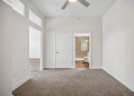 A room with a carpeted floor and a ceiling fan.
