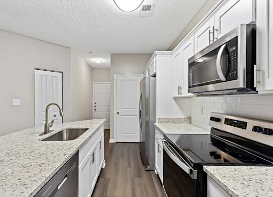 A kitchen with white cabinets and granite countertops.