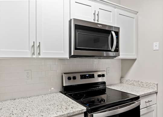 A kitchen with a black microwave oven mounted above a stove.