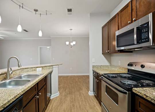 A kitchen with a stove, sink, and microwave.