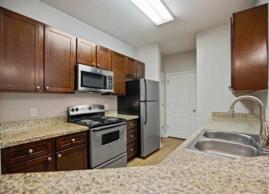A kitchen with brown cabinets and a granite countertop.