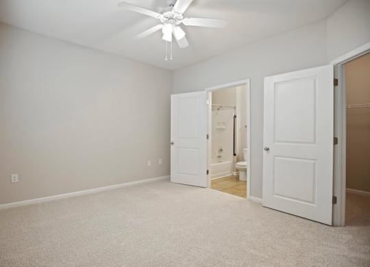 A room with a ceiling fan and three doors.