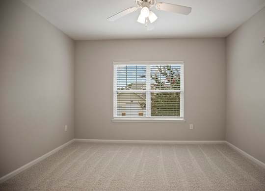 A room with a ceiling fan and a window with blinds.