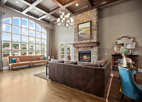 A living room with a brown leather couch and a stone fireplace.