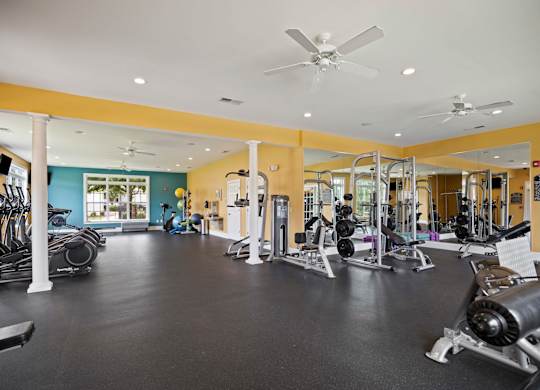 A gym with a variety of equipment including treadmills, weights, and exercise machines.
