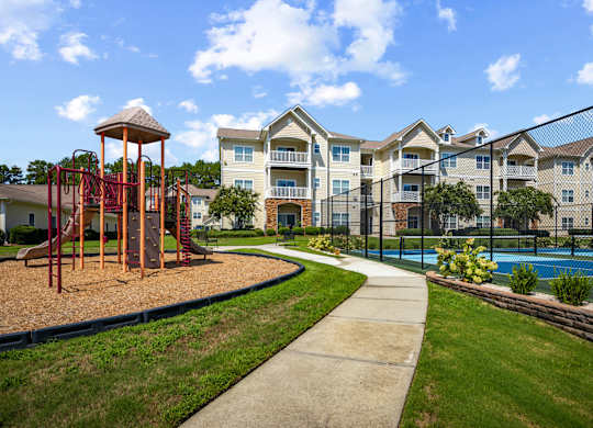 A playground with a swing set and a building in the background.