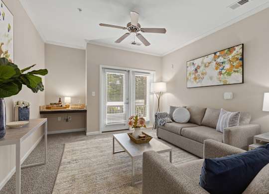 A living room with a beige couch, a coffee table, and a ceiling fan.