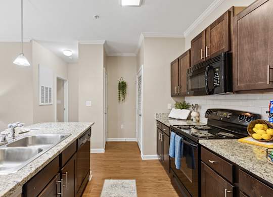 A kitchen with dark wood cabinets and a granite counter top.