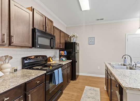 A kitchen with dark wood cabinets and granite countertops.