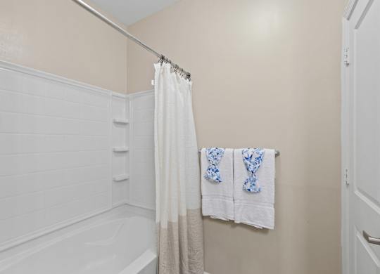 A white bathroom with a white tub and a white shower curtain.