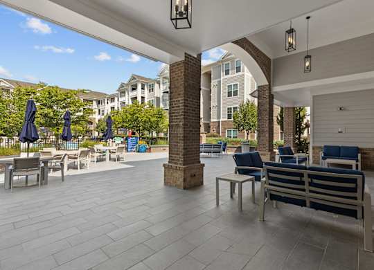 A patio with a table and chairs and umbrellas.