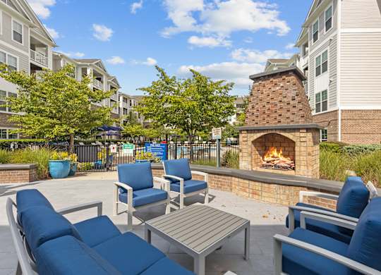 A patio with blue chairs and a fireplace.