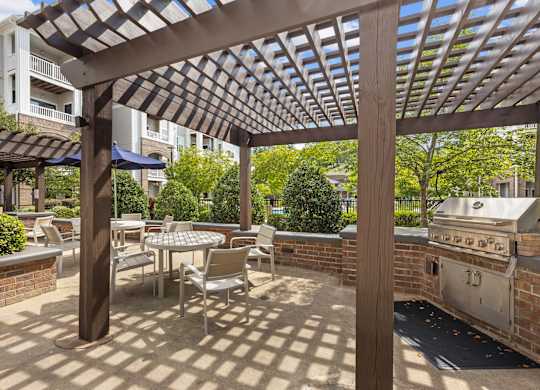 A patio with a table and chairs under a wooden pergola.