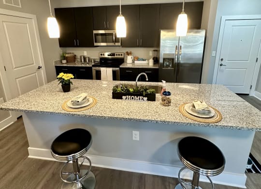 a kitchen with a counter top and stools at Barclay Place Apartments, North Carolina