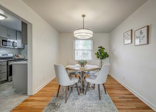 A dining room with a table set for two and a potted plant on the table.