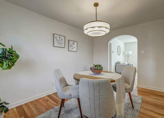 A dining room with a round table and grey chairs.