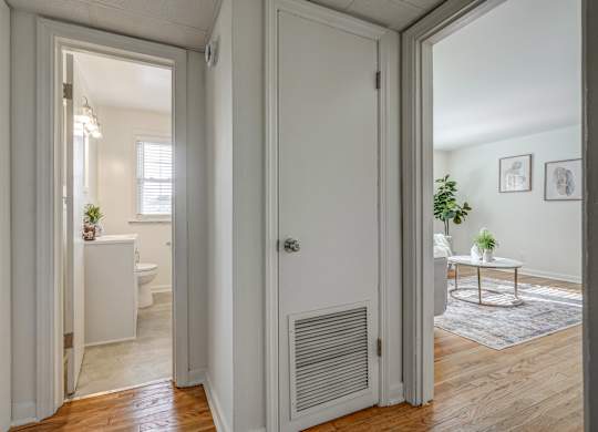A white door is open to a room with a table and a potted plant.