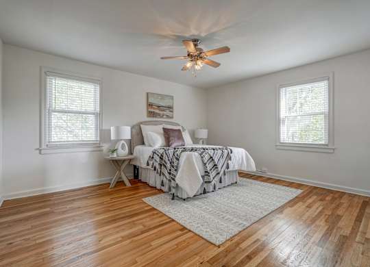 A bedroom with a bed, a fan, and a rug.
