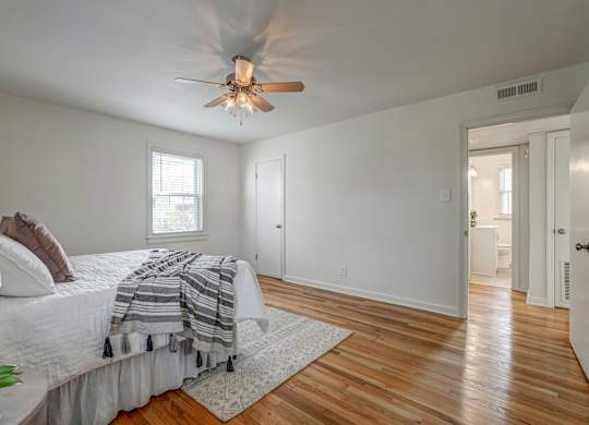 A bedroom with a bed, a ceiling fan, and a rug.