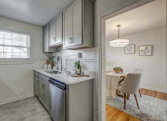 A kitchen with a dining table and chairs in the other room.