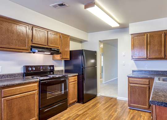 A kitchen with wooden cabinets and a black refrigerator.