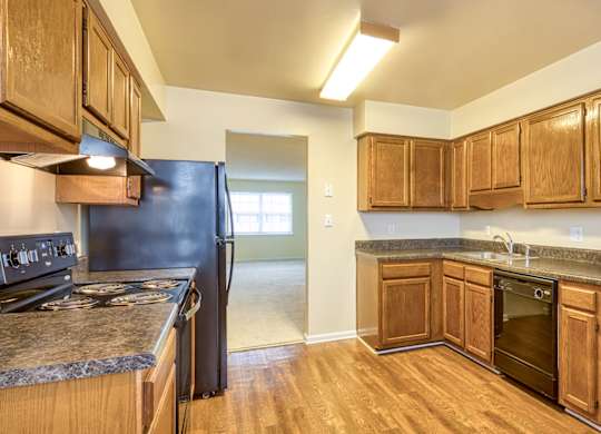 A kitchen with wooden cabinets and a black refrigerator.