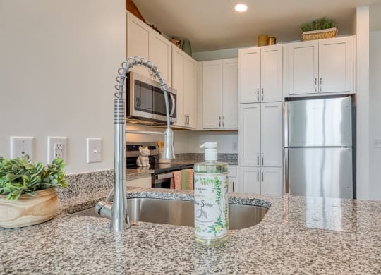 a kitchen with granite counter tops and a stainless steel refrigerator at Allure at Edinburgh, Virginia
