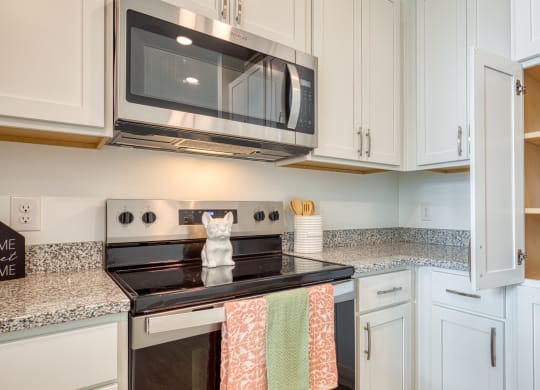 a kitchen with white cabinets and a stove and a microwave at Allure at Edinburgh, Virginia