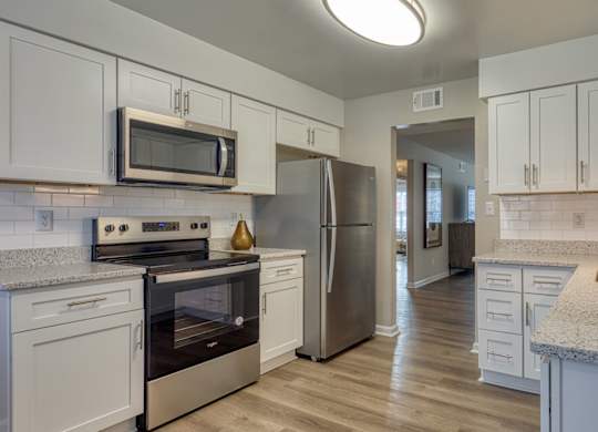 A kitchen with white cabinets and a stainless steel refrigerator.
