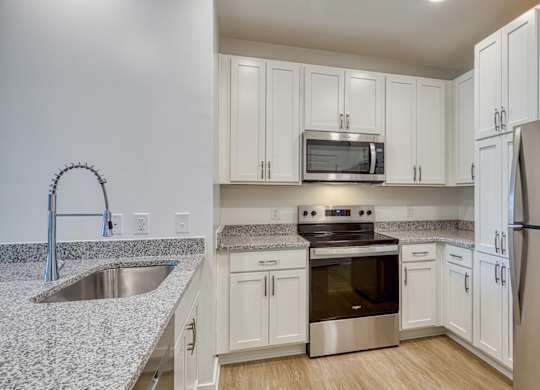 A kitchen with white cabinets and a stainless steel refrigerator.
