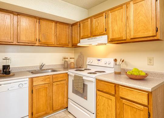 A kitchen with wooden cabinets and white appliances at The Everett  Apartments in Roanoke, Virginia 24018