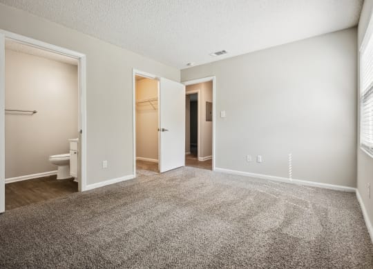 a bedroom with an open door and a bathroom in the background