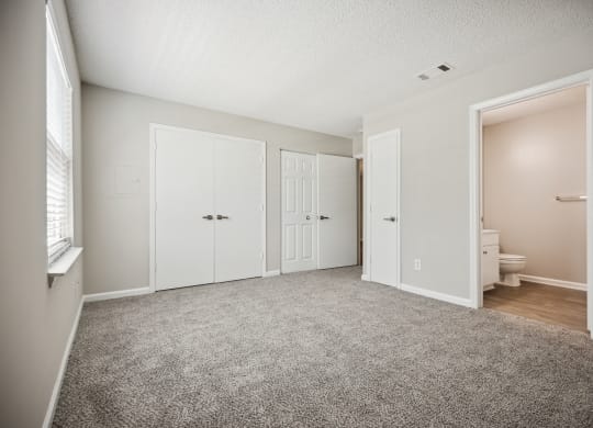 a bedroom with two doors and a bathroom in the background