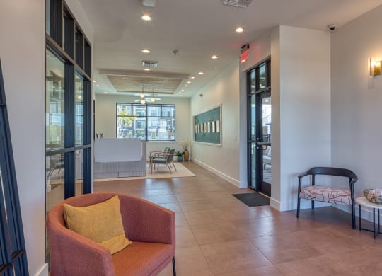 a lobby with a couch and a chair and a hallway with glass doors