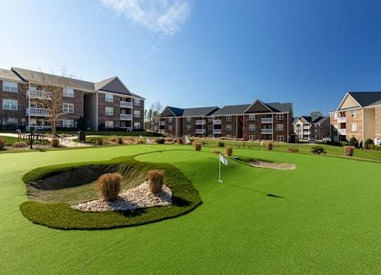 A golf course surrounded by apartment buildings.
