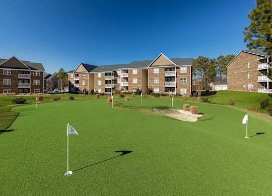 A golf course with a green lawn and two white flags on the tee.